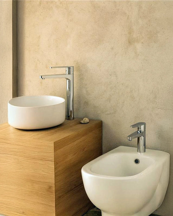 Coppia miscelatori lavabo alto e bidet in ottone senza Cromo Lucido in cromato ambientato su piano bagno con accessori...