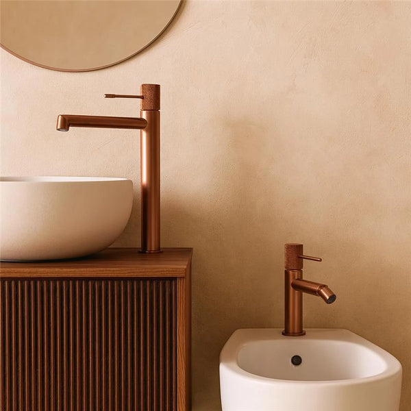 Coppia rubinetti lavabo alto e bidet senza scarico oro rosa in ottone e spazzolato ambientato su piano bagno con...