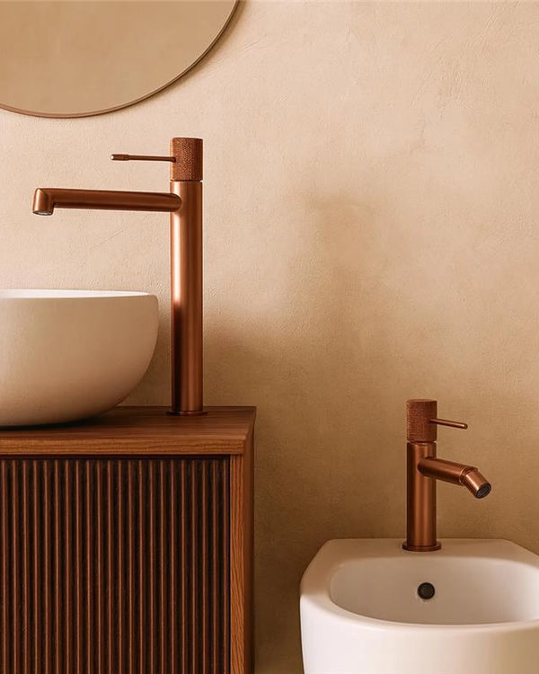 Coppia rubinetti lavabo alto e bidet senza scarico oro rosa in ottone e spazzolato ambientato su piano bagno con...