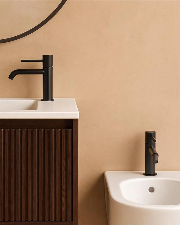 Coppia rubinetti lavabo e bidet senza scarico ottone nero in opaco e satinato ambientato su piano bagno con accessori...