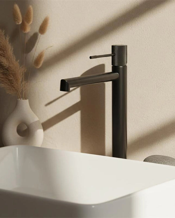 Melin Rubinetto alto per lavabo senza scarico grigio in ottone e naturale ambientato su piano bagno con accessori...