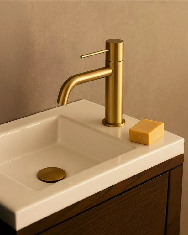Rubinetto lavabo senza scarico in ottone oro spazzolato Memo Oro Mat in satinato ambientato su piano bagno con accessori...