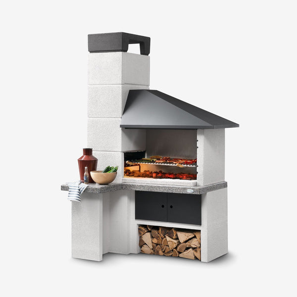 Palazzetti Faro New barbecue con braciere laterale e cappa Grigio accesa in soggiorno, fiamma visibile attraverso il vetro