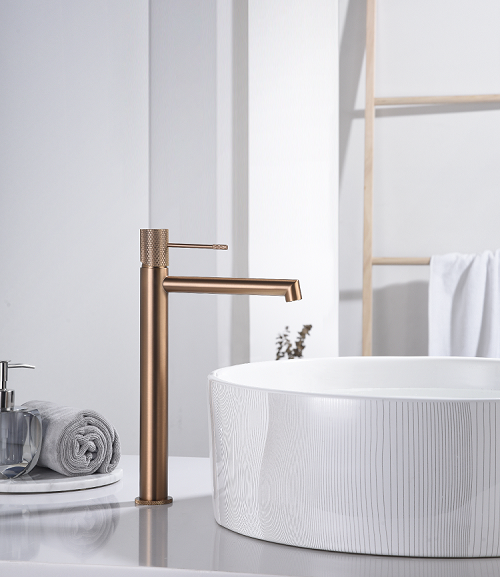 Coppia rubinetti lavabo alto e bidet senza scarico oro rosa ambientato su piano bagno con accessori - Exagonshop