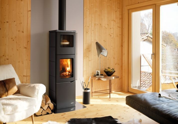 Stufa A Legna Con Forno ad aria 8kw rivestimento in Acciaio accesa in soggiorno, fiamma visibile attraverso il vetro