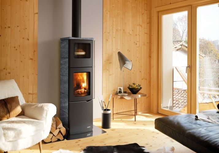 Stufa A Legna Con Forno ad aria 8kw rivestimento Pietra accesa in soggiorno, fiamma visibile attraverso il vetro