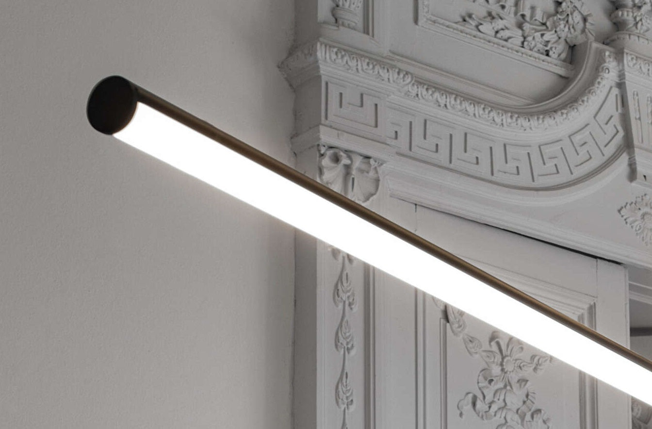 Flos Arrangements Line Lampada a sospensione 170 cm nero in alluminio accesa in ambiente, design e diffusione della luce