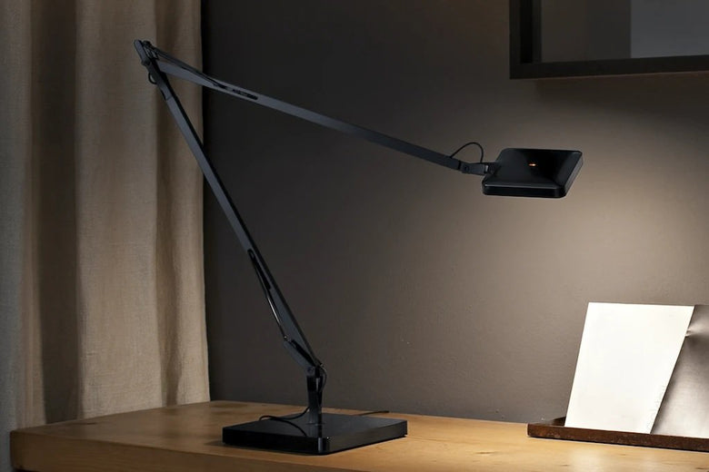 Flos Kelvin Edge Base Lampada scrivania nero in alluminio accesa in ambiente, design e diffusione della luce