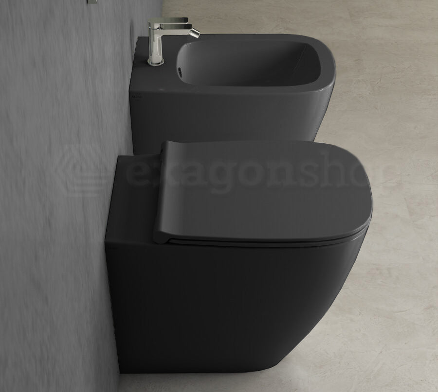Globo Genesis Coppia Sanitari filoparete Vaso senza brida E in ceramica ambientato su piano bagno con accessori...