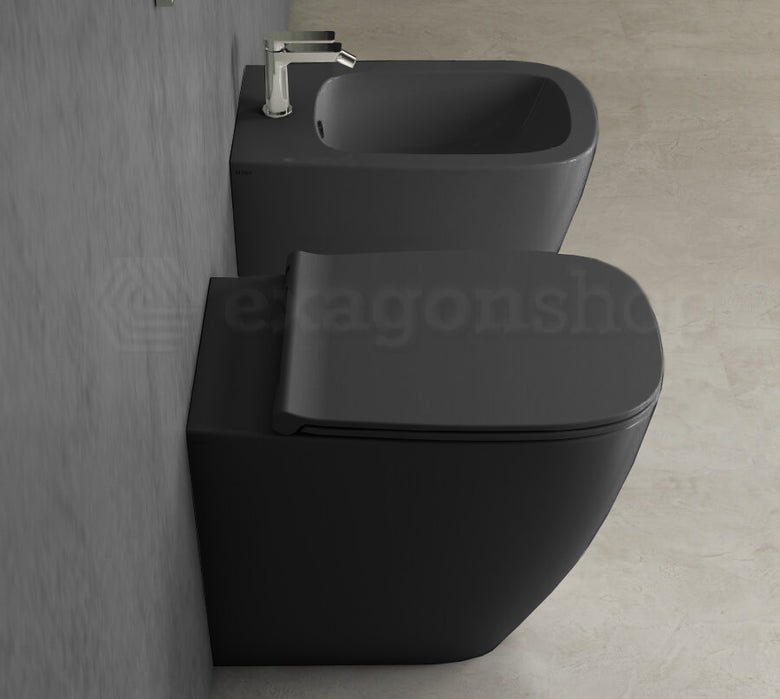 Globo Genesis Coppia Sanitari filoparete Vaso senza brida E in ceramica ambientato su piano bagno con accessori...