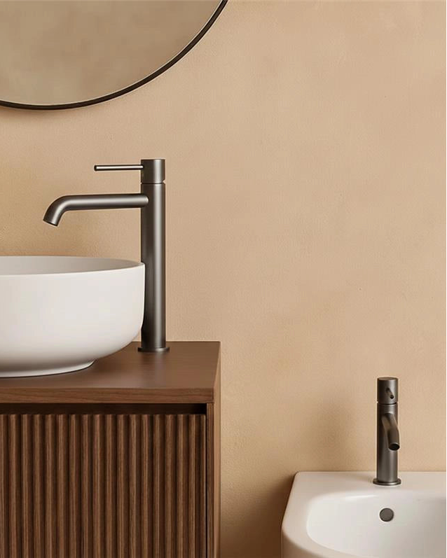 Coppia rubinetti lavabo alto e bidet senza scarico grigio in ottone ambientato su piano bagno con accessori - Exagonshop