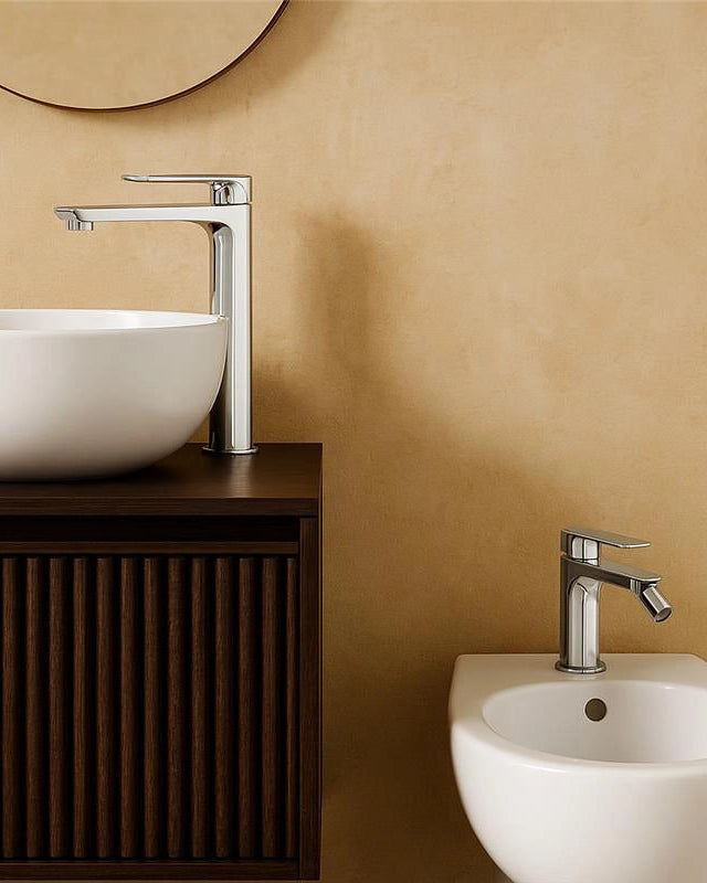 Coppia rubinetti miscelatore lavabo alto e bidet senza Cromo Lucido in ottone ambientato su piano bagno con accessori...