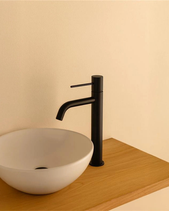 Rubinetto lavabo alto monocomando in ottone nero opaco ambientato su piano bagno con accessori - Exagonshop