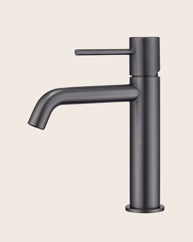 Rubinetto lavabo senza scarico ottone grigio metallico Memo Canna Di Fucile ambientato su piano bagno con accessori...