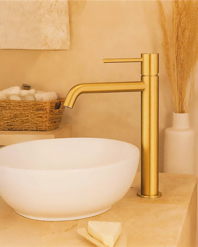 Rubinetto alto per ciotola senza scarico ottone oro Oro Mat in spazzolato e naturale ambientato su piano bagno con...