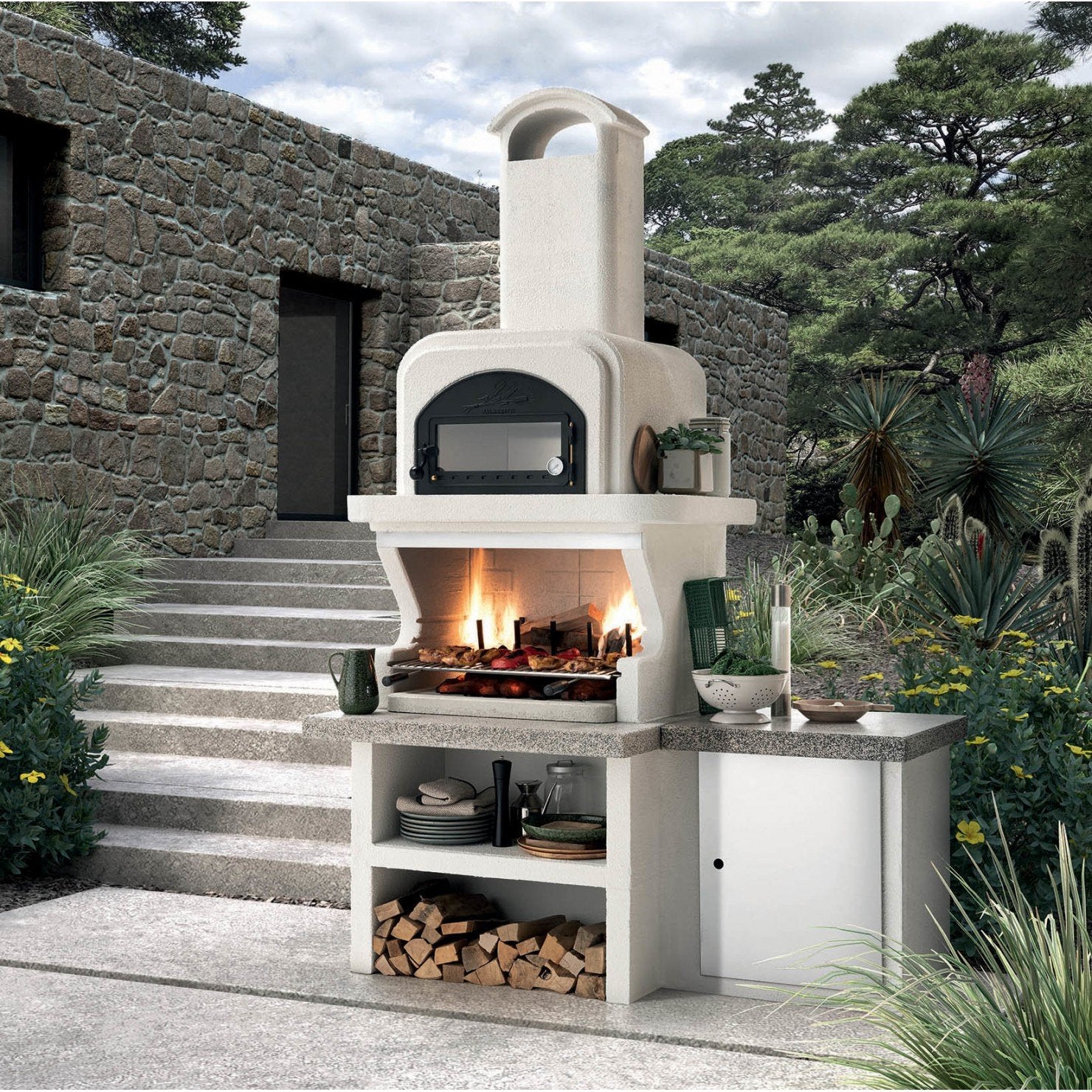 Palazzetti Capri 3 barbecue a legna con forno e piano in in acciaio inox accesa in soggiorno, fiamma visibile attraverso...