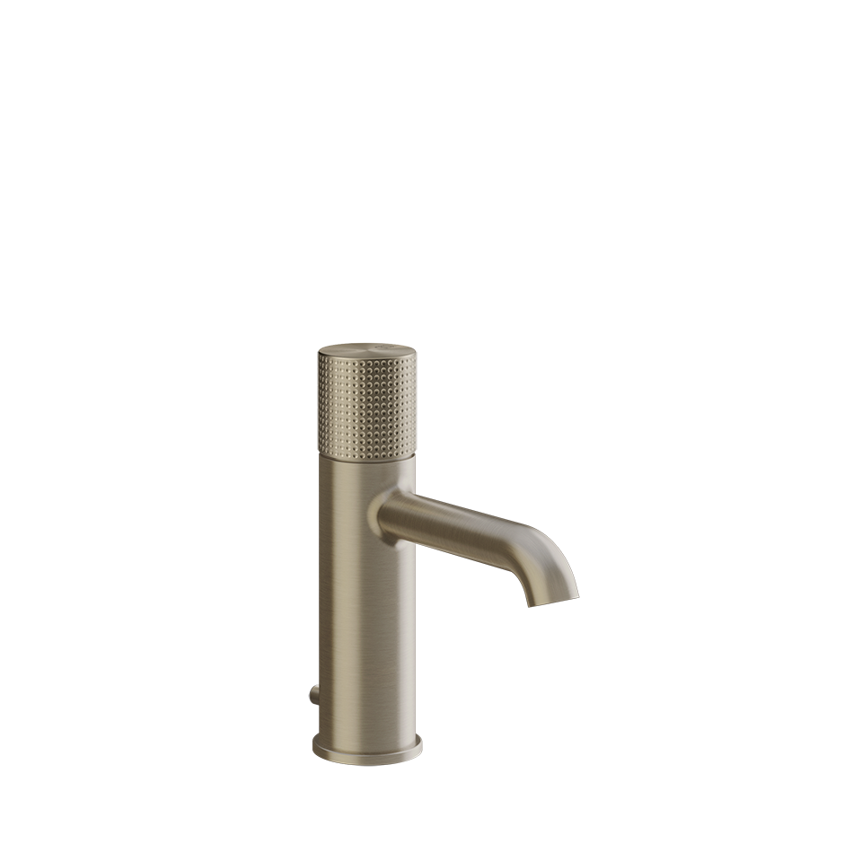 Gessi Cesello Miscelatore lavabo con scarico brushed brass ambientato su piano bagno con accessori