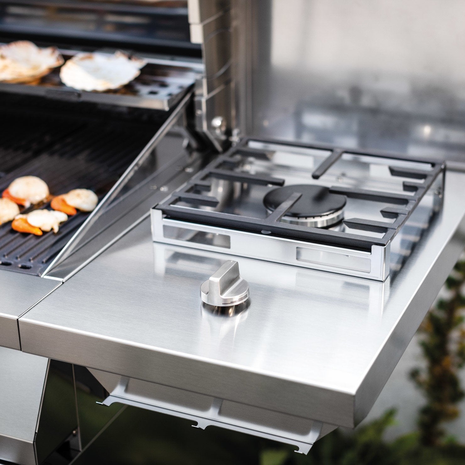 Palazzetti Alain barbecue a gas tre griglie con ruote Acciaio accesa in soggiorno, fiamma visibile attraverso il vetro