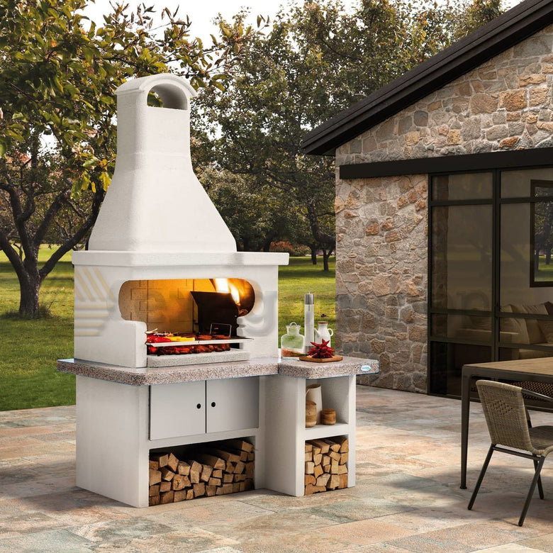 Palazzetti Tropea 4 barbecue a legna piano in Marmotech accesa in soggiorno, fiamma visibile attraverso il vetro