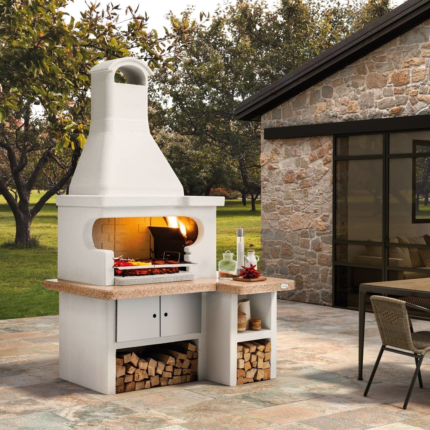 Palazzetti Tropea 4 barbecue a legna piano in Marmotech accesa in soggiorno, fiamma visibile attraverso il vetro