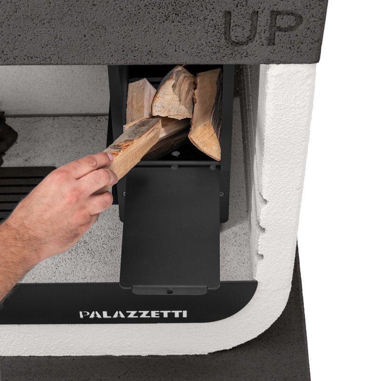 Palazzetti Up barbecue a legna grezzo in Marmotech bianco e accesa in soggiorno, fiamma visibile attraverso il vetro